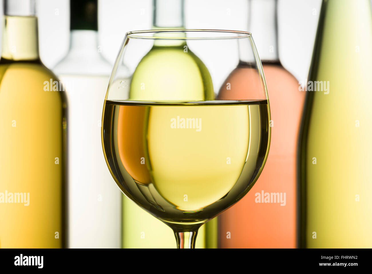 Becher mit Weißwein und Flaschen auf Hintergrund Stockfoto