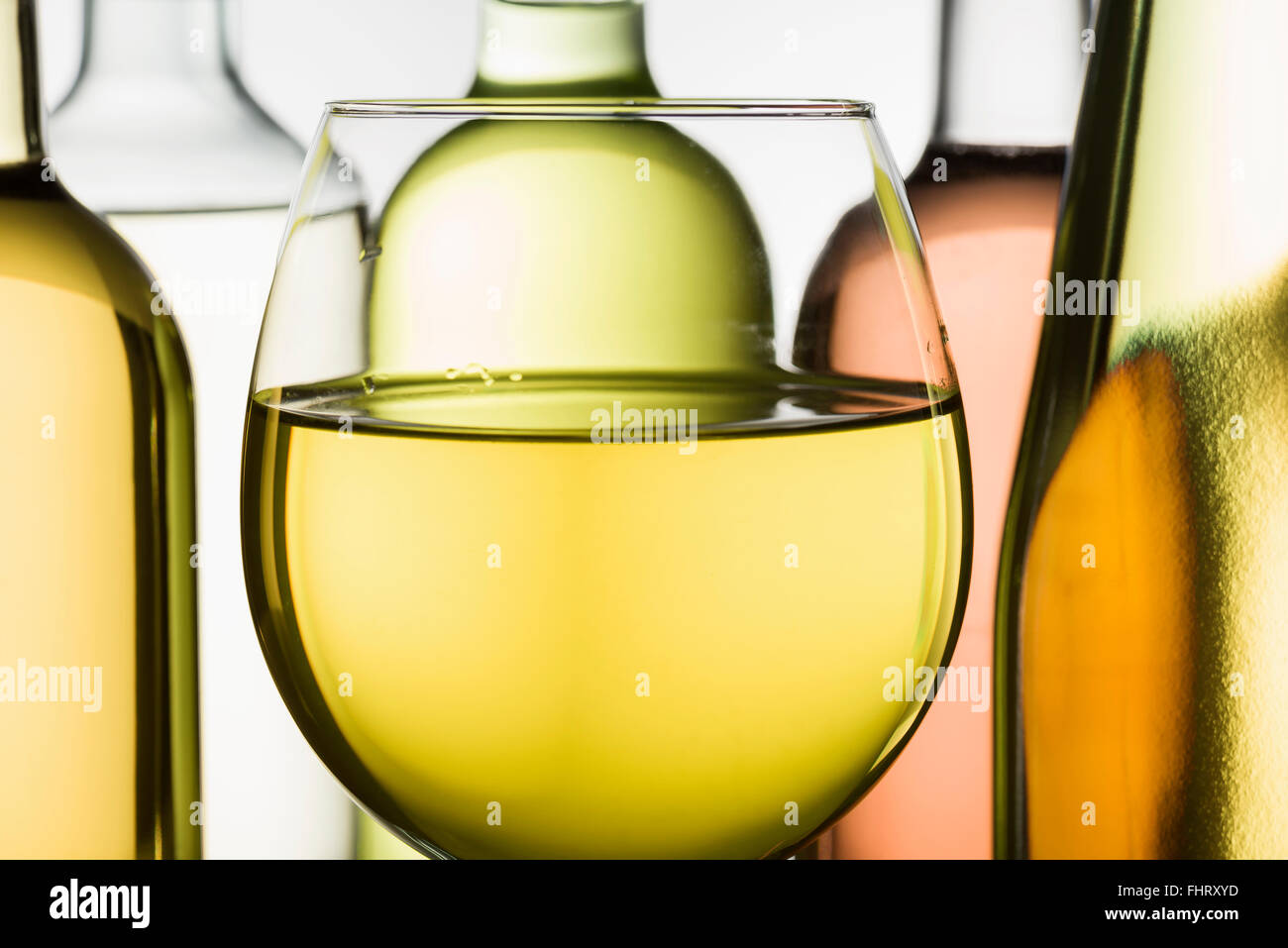 Becher mit Weißwein und Flaschen auf Hintergrund Stockfoto