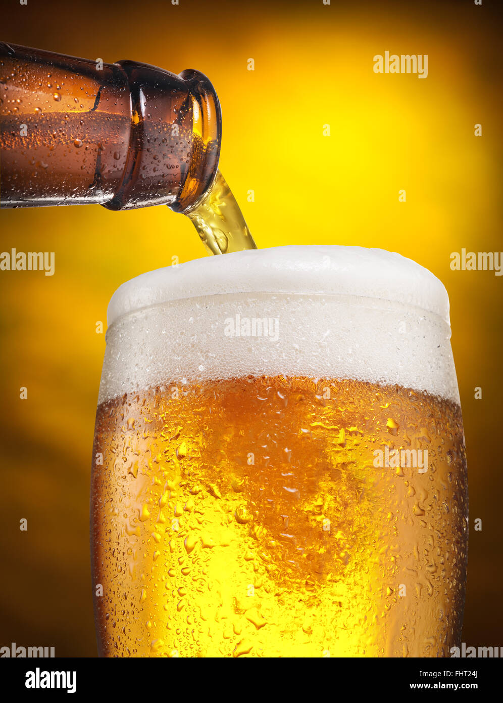 Der Prozess der strömenden Bier in das Glas. Leuchtend orange Hintergrund. Stockfoto