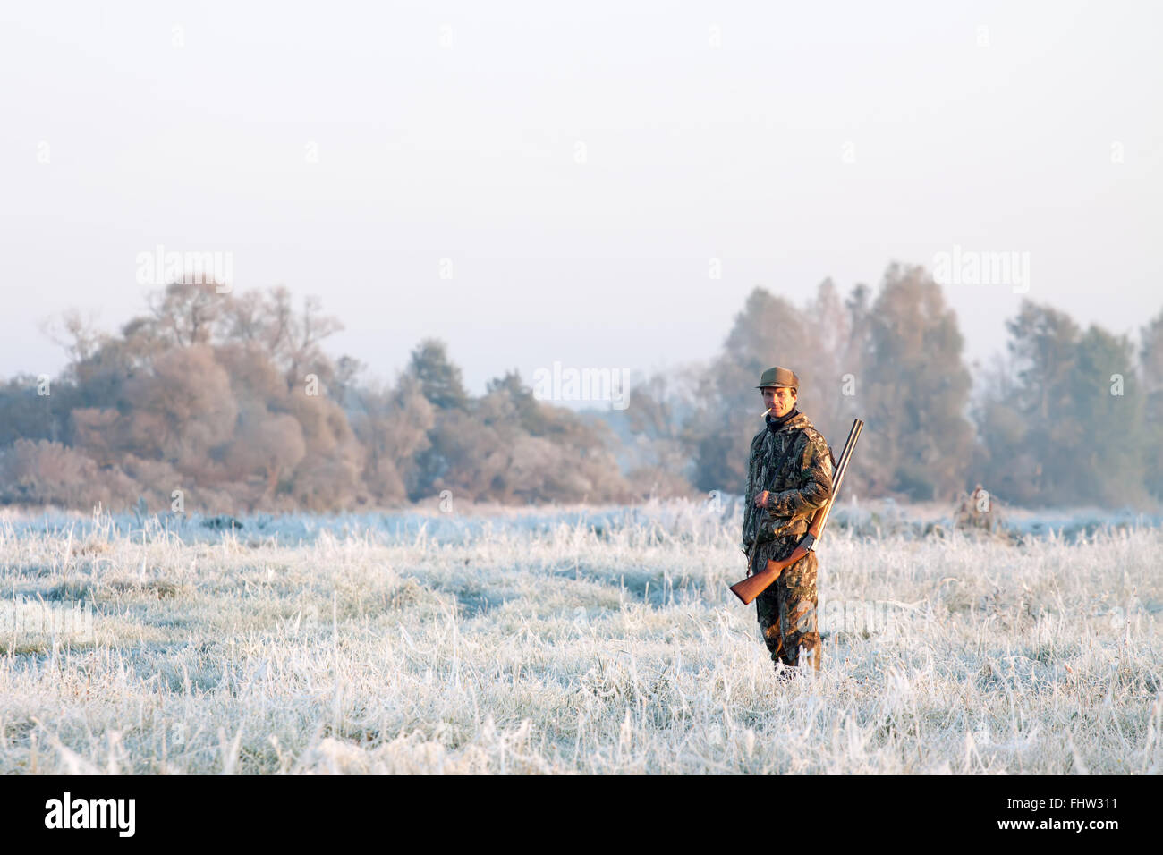 Hunter in Tarnung mit einer Schrotflinte auf seiner Schulter im Winter auf eine Winterlandschaft Stockfoto