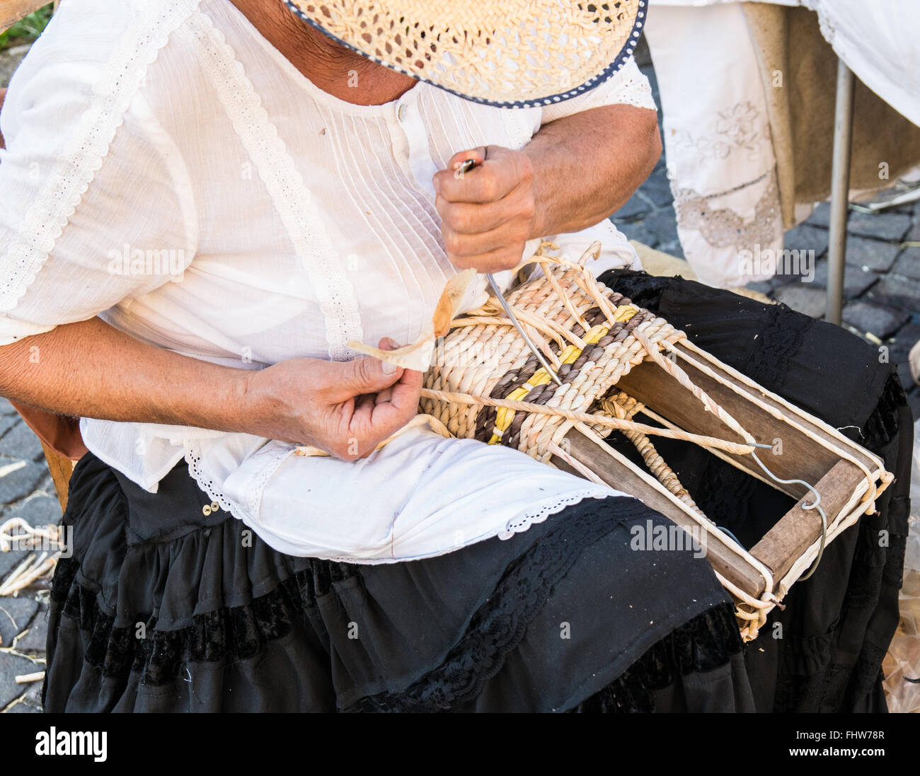 Ältere Dame baut Taschen mit den getrockneten Blättern der Maiskolben von Hand gewebt. Stockfoto