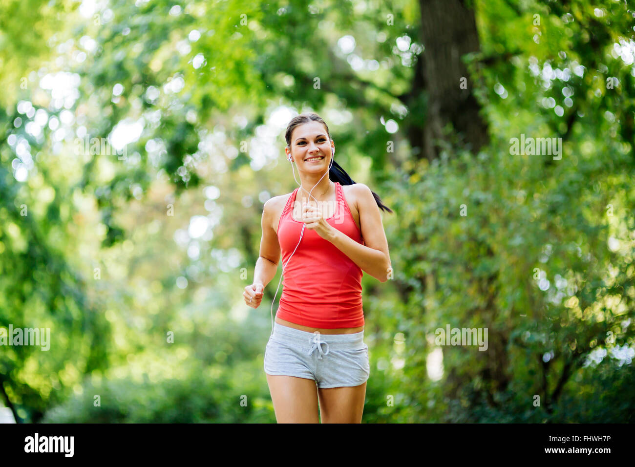 Junge schöne Athlet im Park Joggen und etwas Musik hören während der Tätigkeit Stockfoto