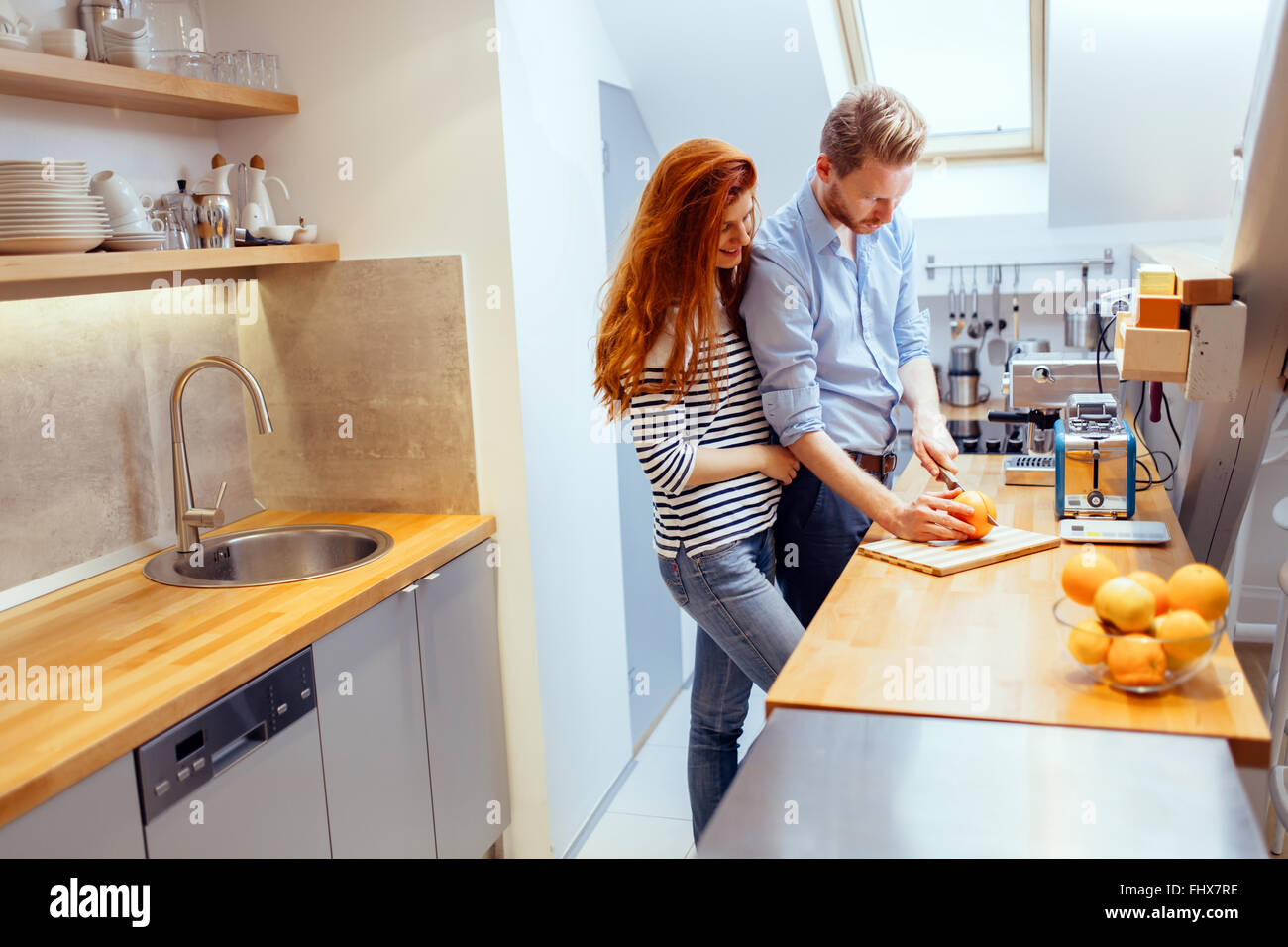 Paar macht orange Smoothie in Küche aus frischen Orangen Stockfoto