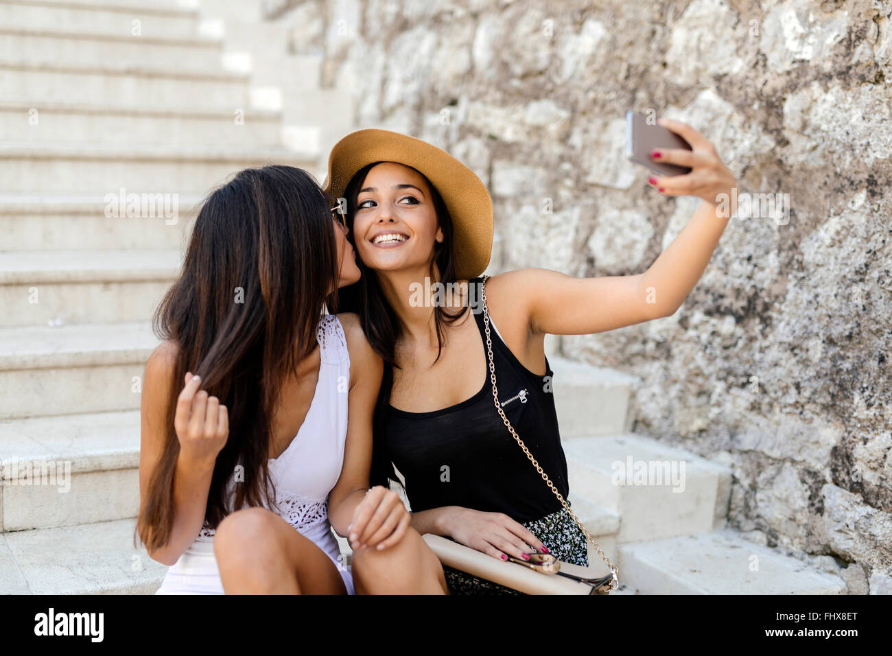 Zwei junge attraktive Frauen, die die Selfies von selbst auf Treppen im Sommer Stockfoto