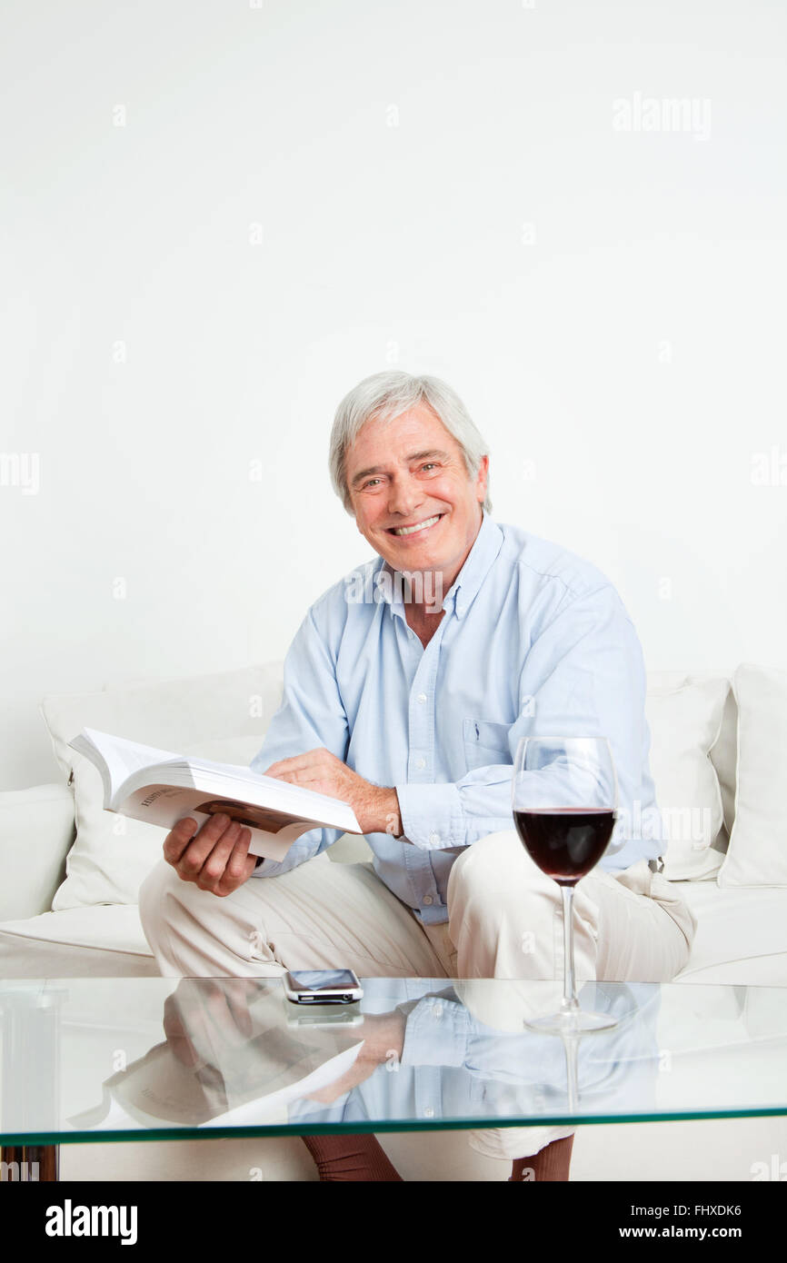 Happy senior woman ein Bestseller-Buch auf couch Stockfoto