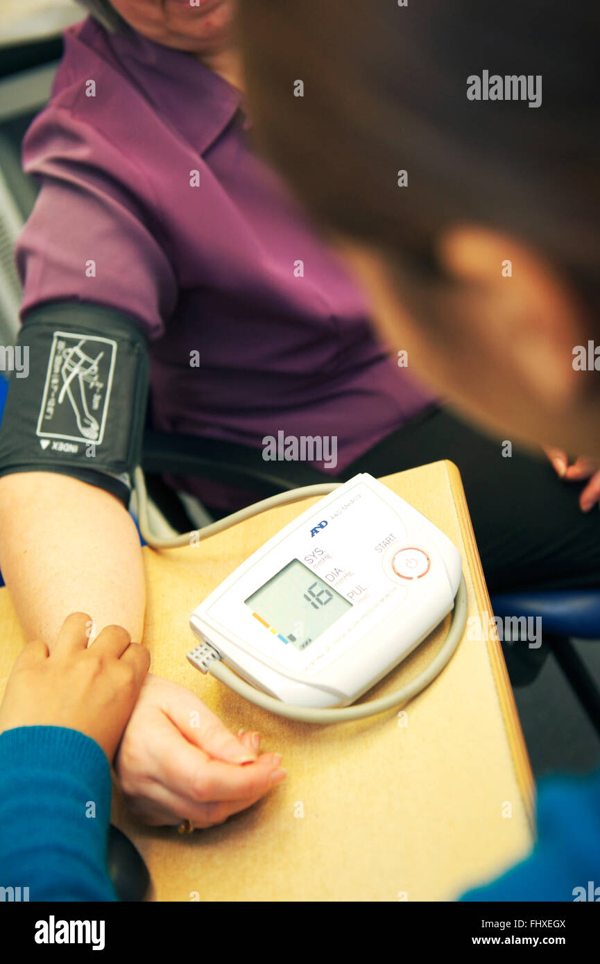 Arzt nimmt Patienten Blutdruck im Gesundheitszentrum in UK Stockfoto