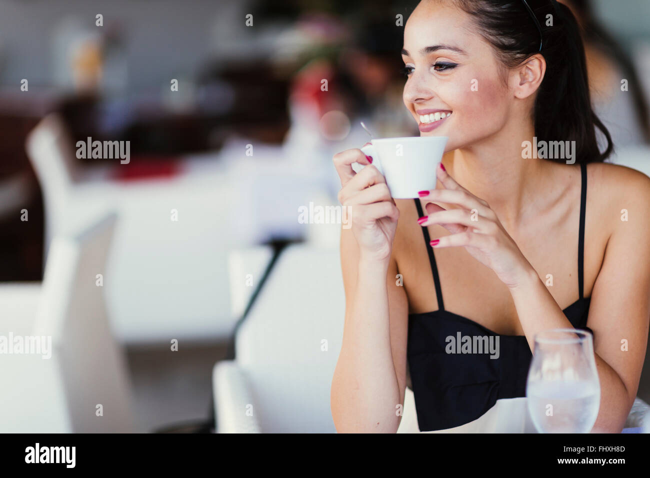 Schöne Frau trinkt Tee im Restaurant während des Wartens auf ihre Mahlzeit Stockfoto