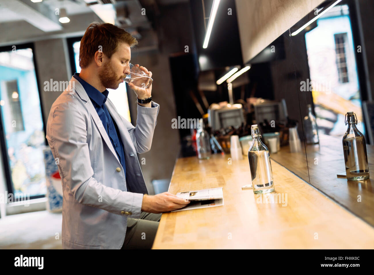 Geschäftsmann, Trinkwasser und Morgenzeitung lesen Stockfoto