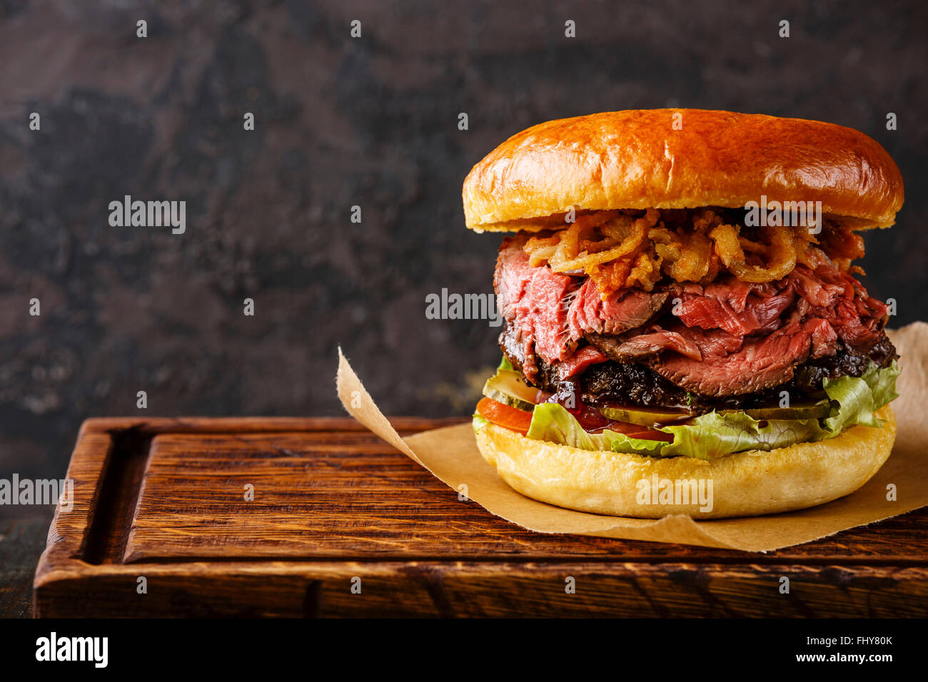 Pastrami Burger geschnittenes Roastbeef mit Zwiebeln Pommes frites Ringe auf schwarzem Hintergrund Stockfoto