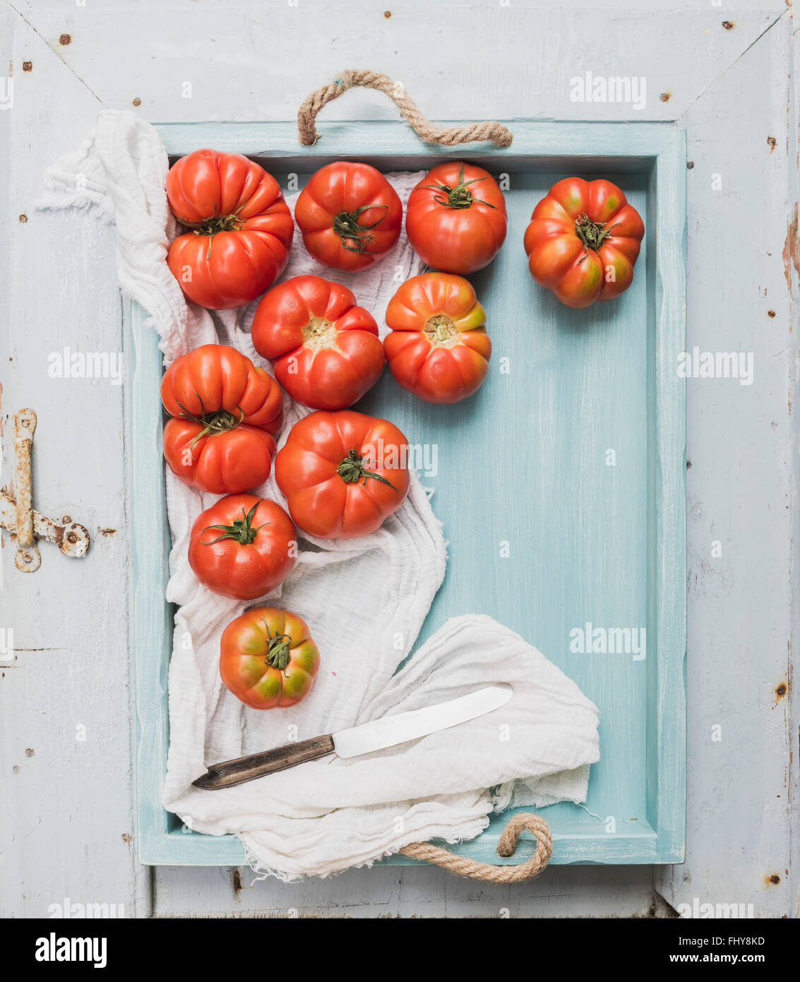 Frische reife Hairloom Tomaten in Türkis Holztablett auf blau aus Holz Oberfläche Draufsicht Stockfoto