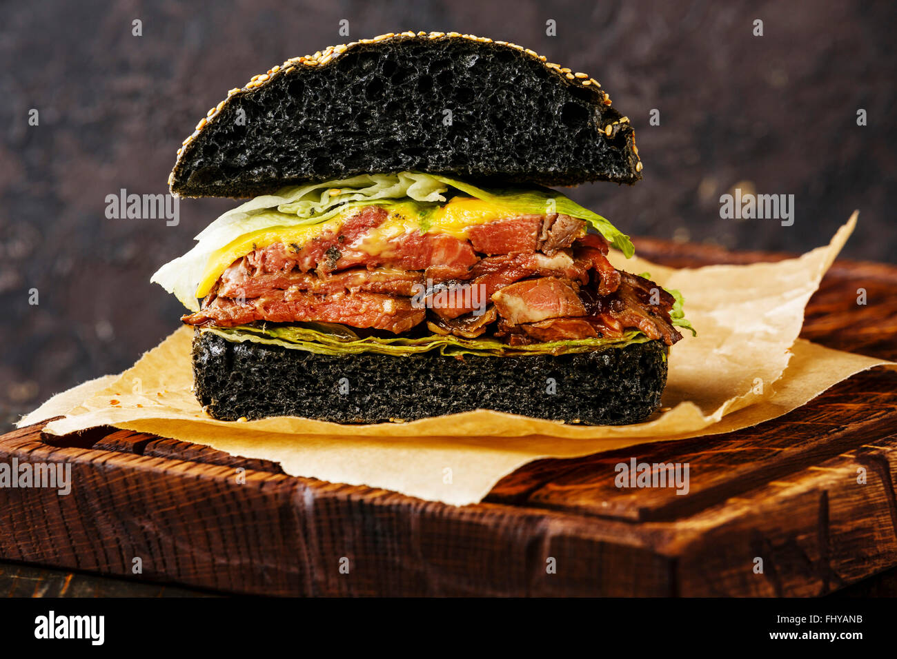 Schneiden Sie in halbe Roastbeef Burger mit in Scheiben geschnittenen Pastrami auf dunklem Hintergrund Stockfoto