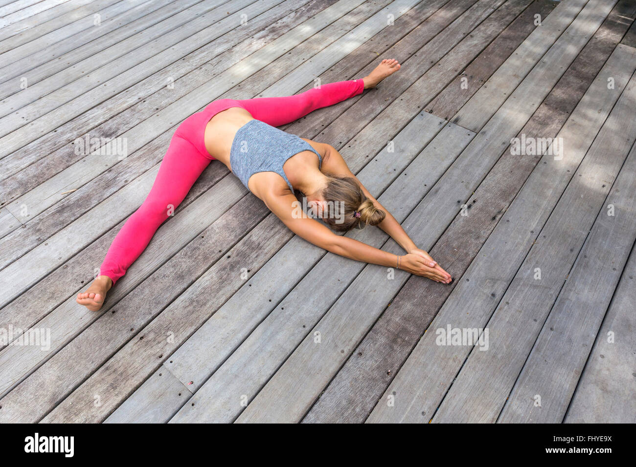 Frau im Yoga straddle Position auf deck Stockfoto