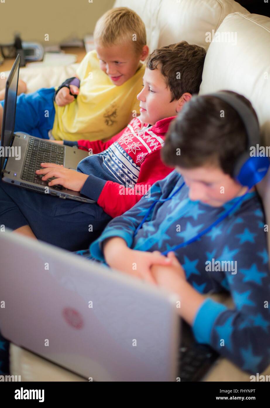-MODELL VERÖFFENTLICHT. Drei Jungs mit Laptop auf dem Sofa sitzen. Stockfoto
