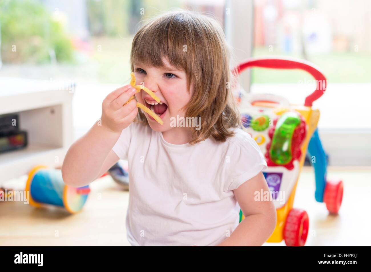 -MODELL VERÖFFENTLICHT. Junges Mädchen essen Pommes Frites. Stockfoto