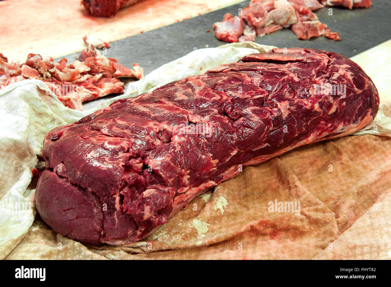 Großes Stück getrimmte Roastbeef auf Tisch mit fetten Brocken im Hintergrund Stockfoto