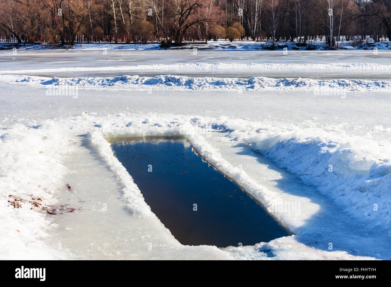 Eisloch im zugefrorenen See im sonnigen Wintertag Stockfoto