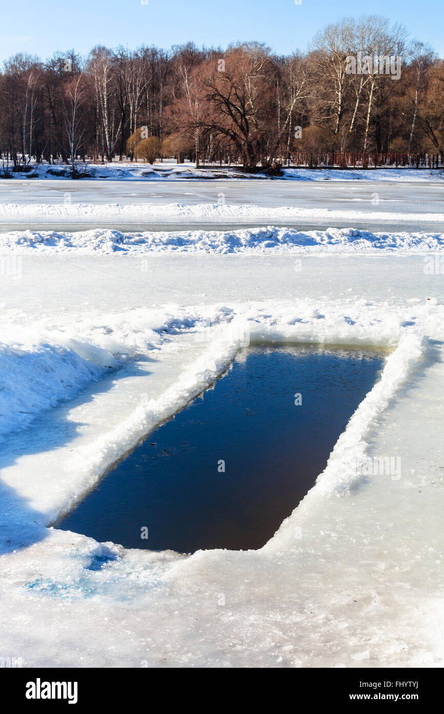 Eisloch im gefrorenen Fluss im sonnigen Wintertag Stockfoto