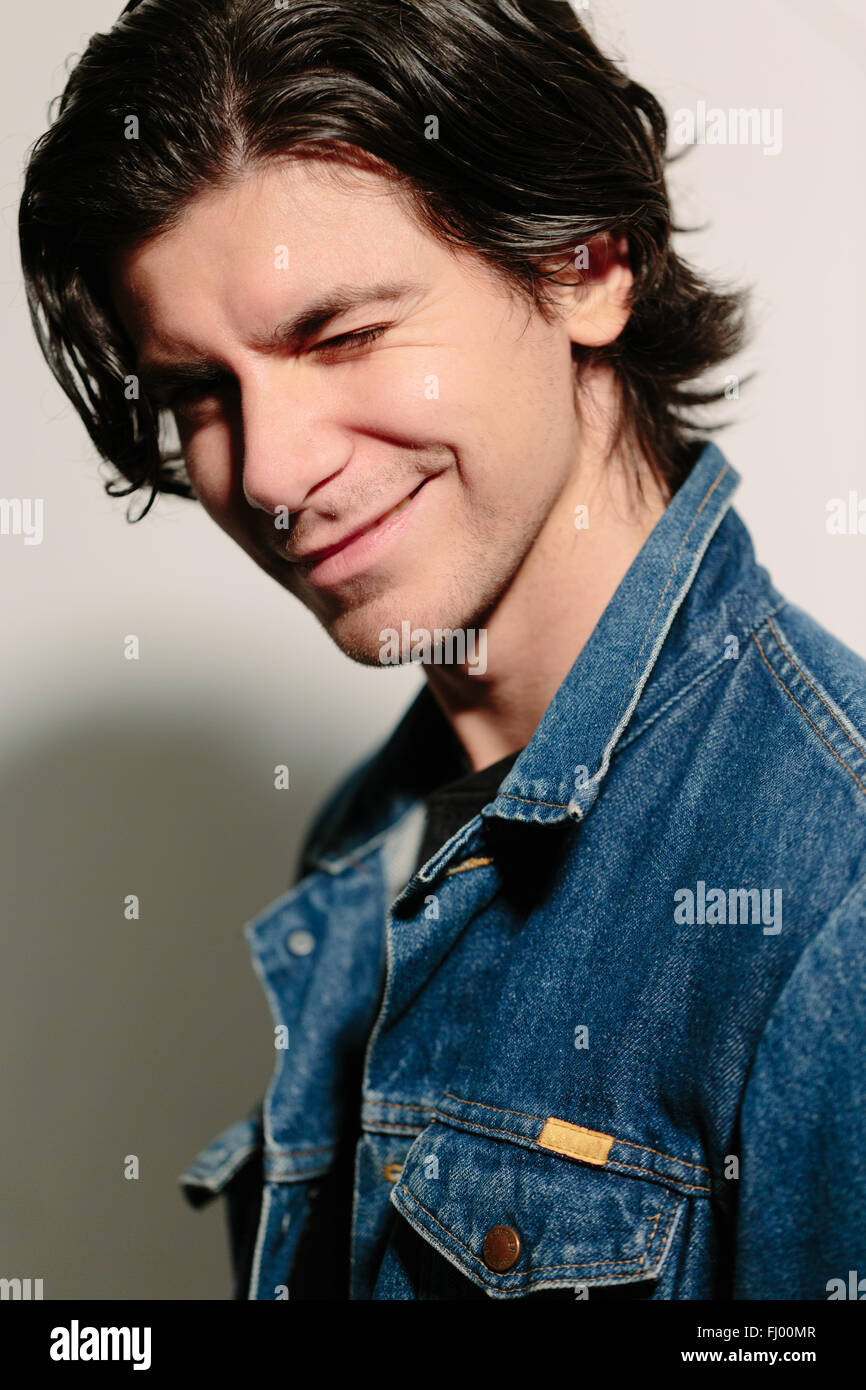 Hübscher junger Mann in eine Jeans Jacke lächelt. Stockfoto