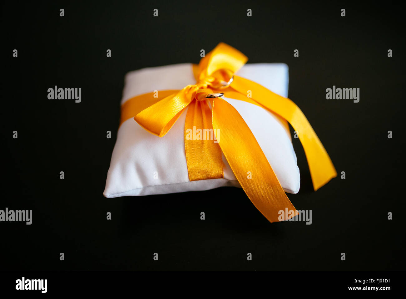 gelbes Kissen für die Ringe auf weißen Kissen Stockfoto