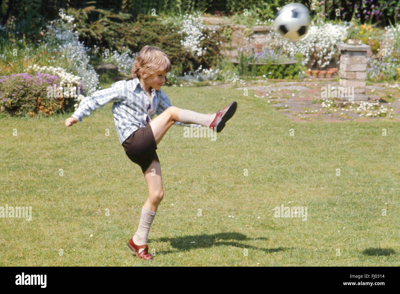 Junge, sechs, kicken Fußball in Garten, 1974 Stockfoto