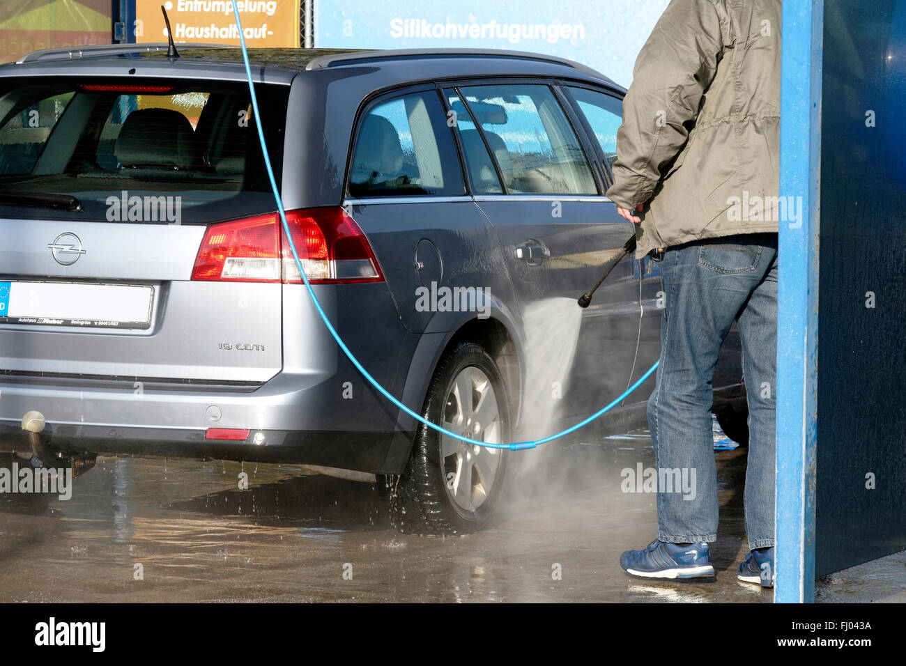 Mann Reinigung Auto mit Wasser Druckschlauch, Oberbayern, Deutschland, Stockfoto