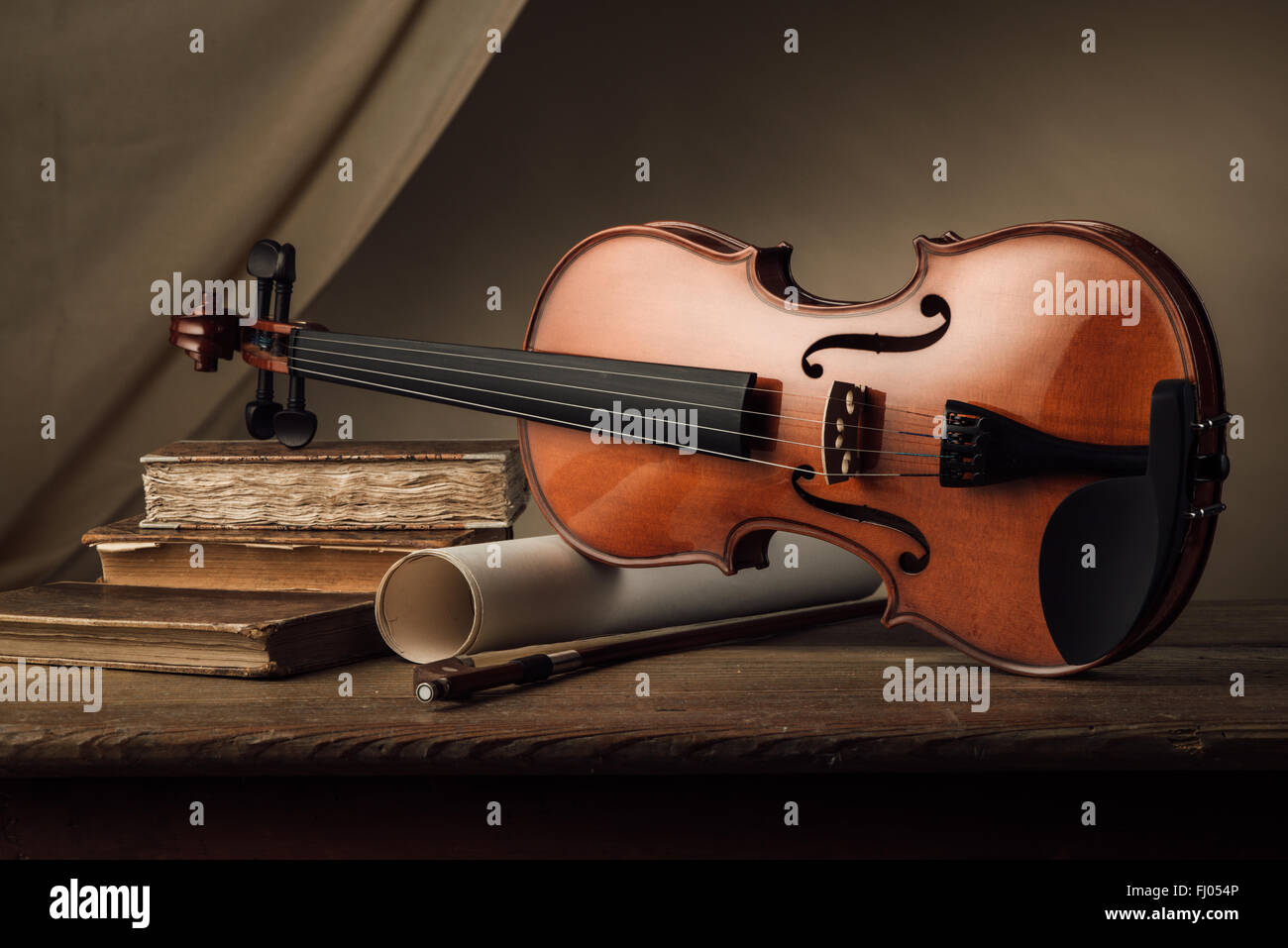 Alte Geige mit Bogen Musikrollen und alte Bücher auf einem Holztisch, Stillleben Stockfoto