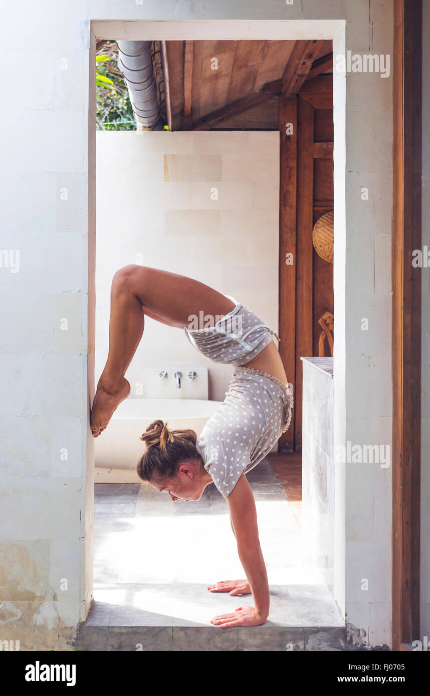 Frau macht einen Handstand im Türrahmen Stockfoto