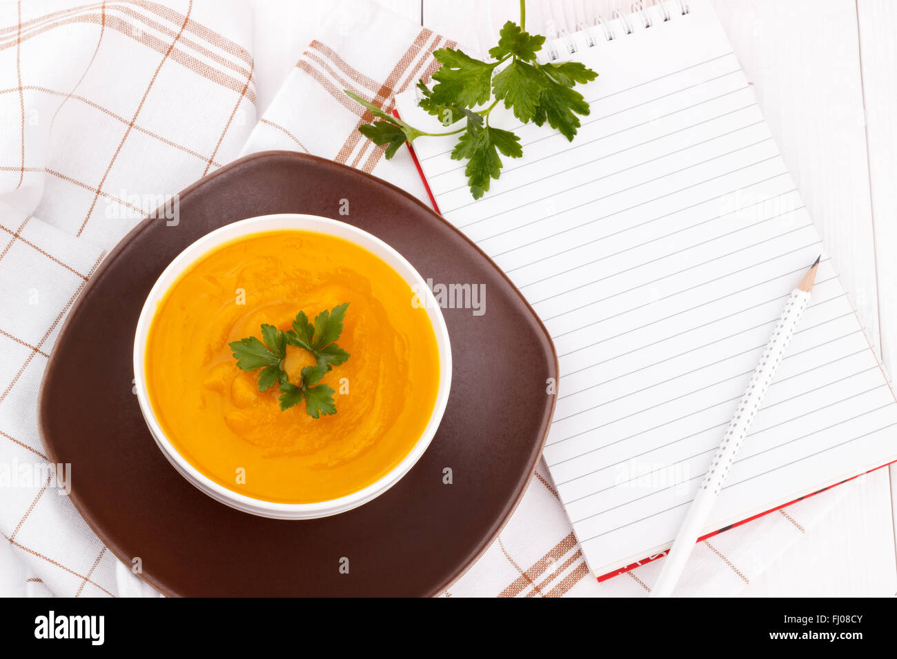 Kürbissuppe mit Bleistift auf weißer Holztisch und leere Rezeptbuch Stockfoto