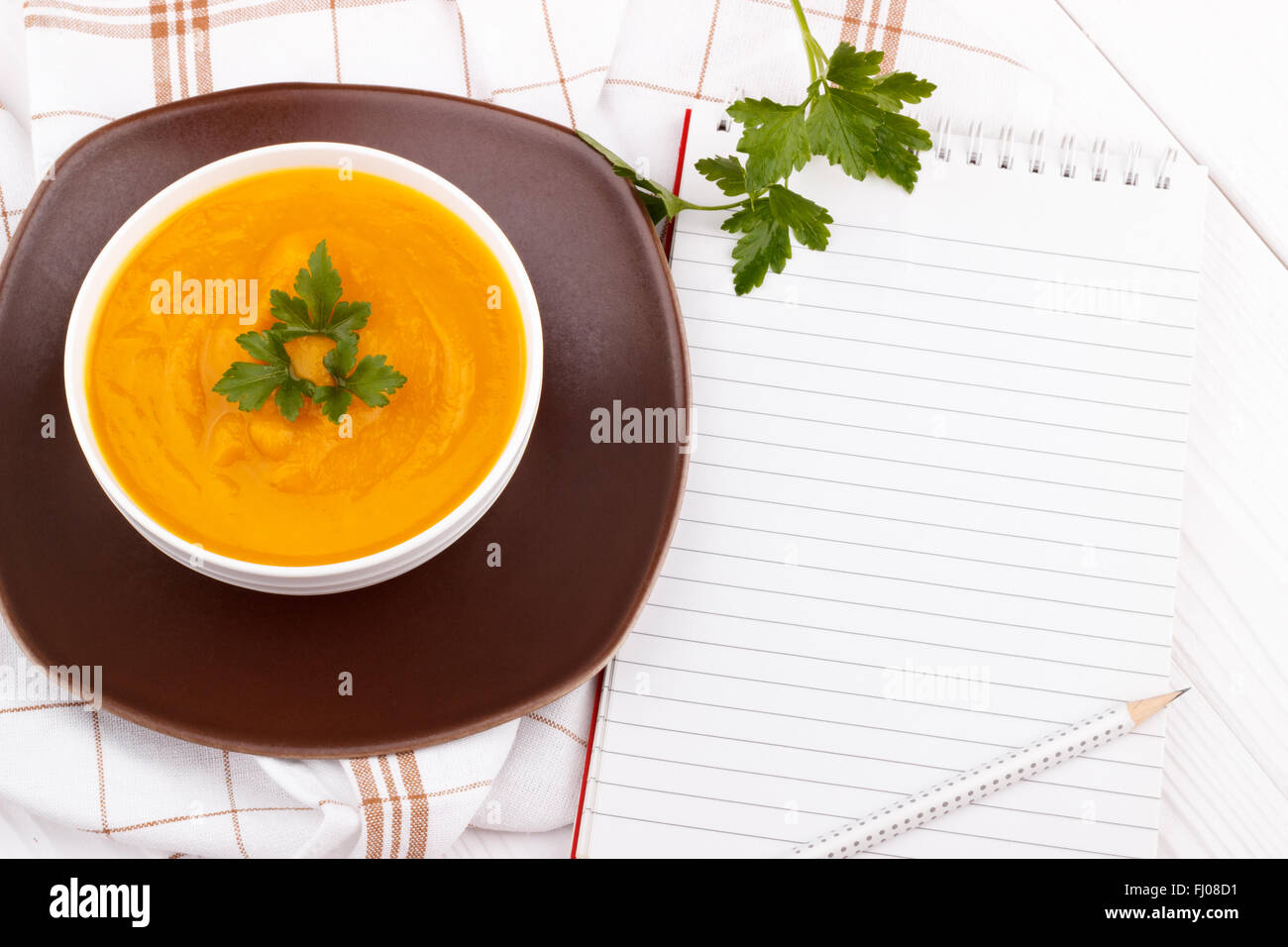 Kürbissuppe mit Bleistift auf weißer Holztisch und leere Rezeptbuch Stockfoto