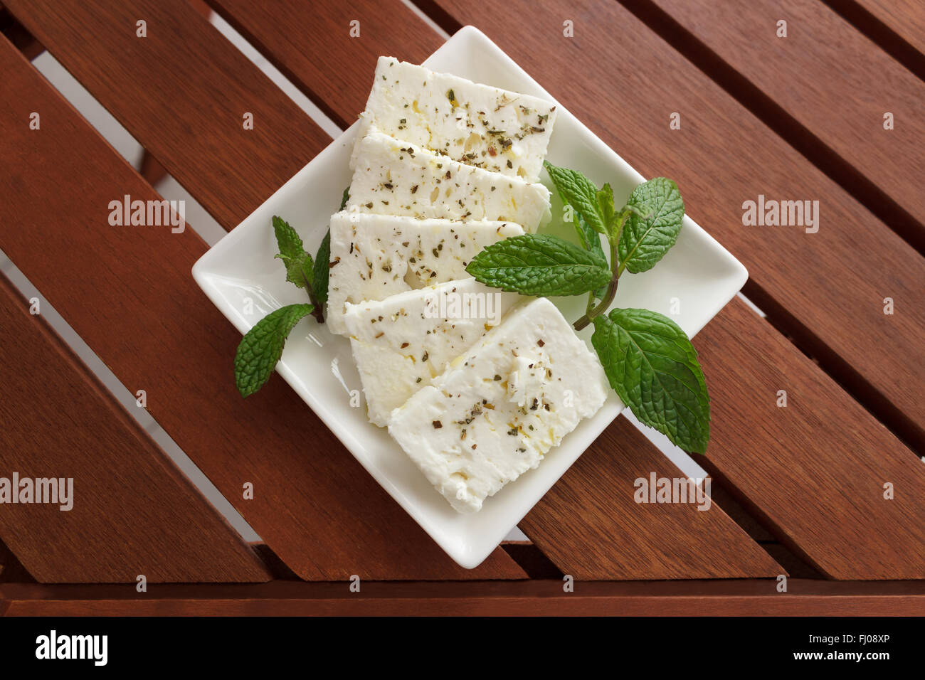 Griechischer Feta-Käse auf einem weißen Teller mit Oregano und Minze Stockfoto