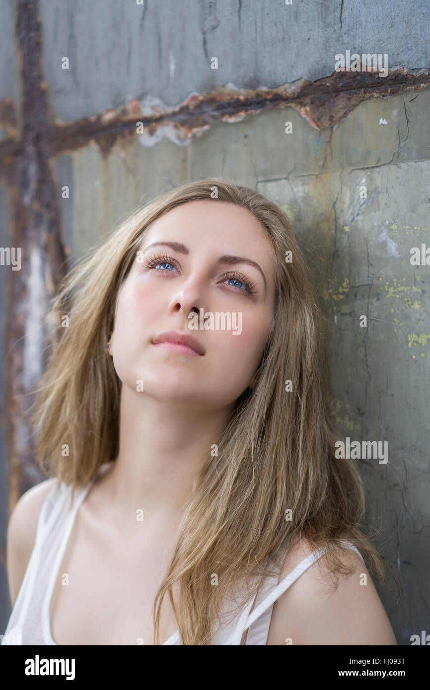 Junge Frau, die eine rostige Wand gelehnt Stockfoto