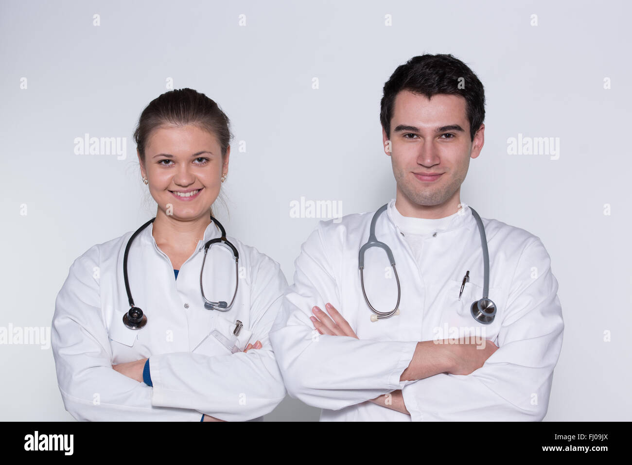 zwei junge Ärzte, männlich und weiblich in weißen Kitteln mit Stethoskop Stockfoto
