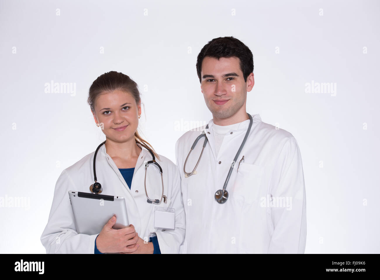 zwei junge Ärzte, männlich und weiblich in weißen Kitteln mit Stethoskop mit Tablet-pc arbeiten Stockfoto