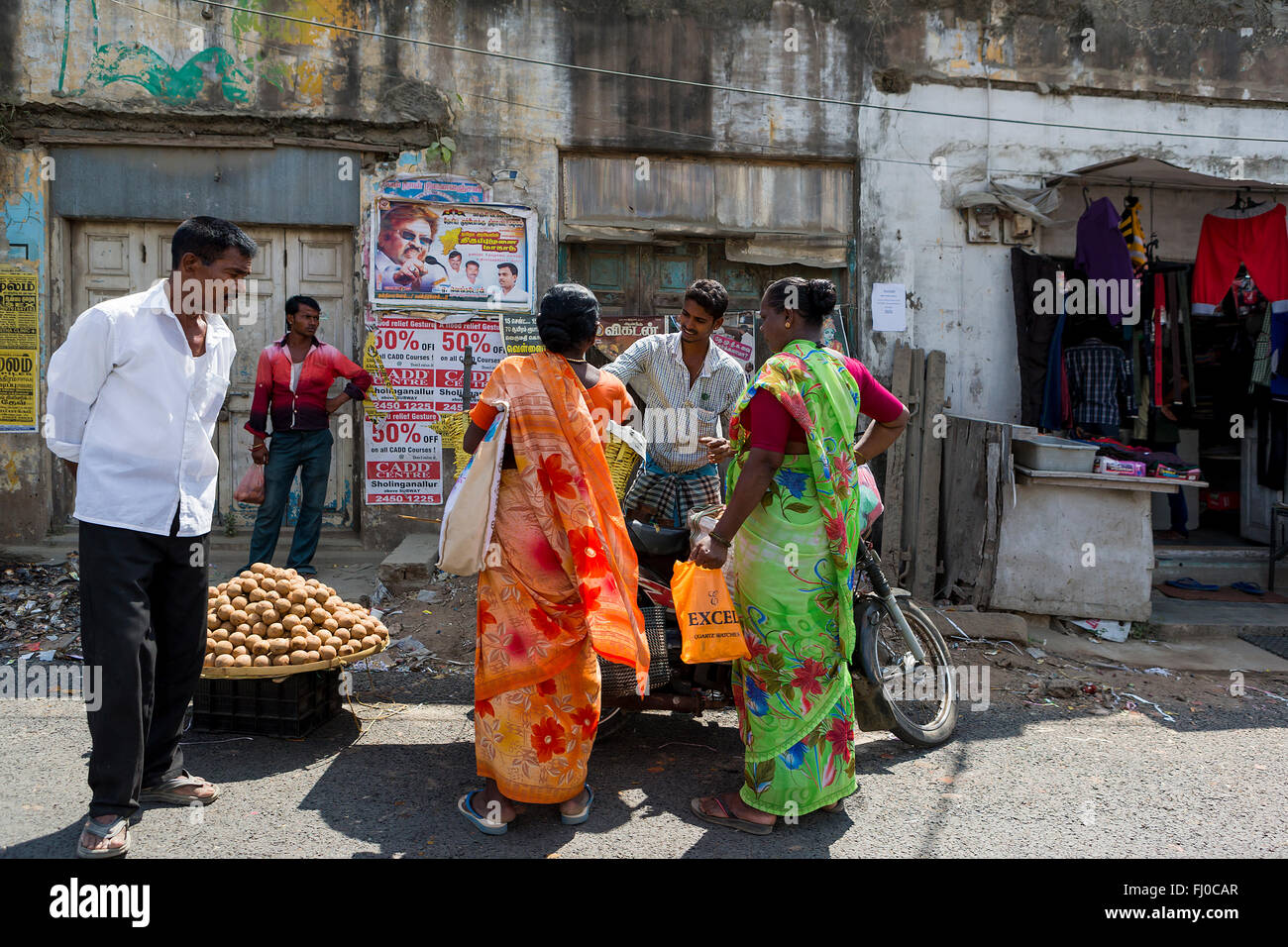 Eine Gruppe des indischen Volkes stehen und sprechen um ein Motorrad vor den Geschäften am Straßenrand in der Nähe von Chennai Stockfoto