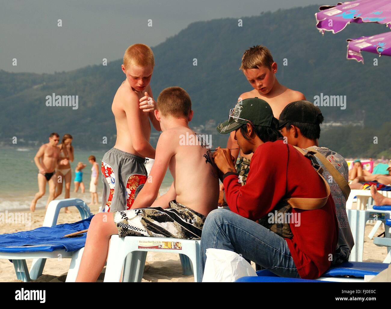 Patong / Phuket, Thailand: Thai Tattoo-Künstler gilt temporäre Tattoos zu einer Familie von schwedischen Touristen am Patong Beach Stockfoto