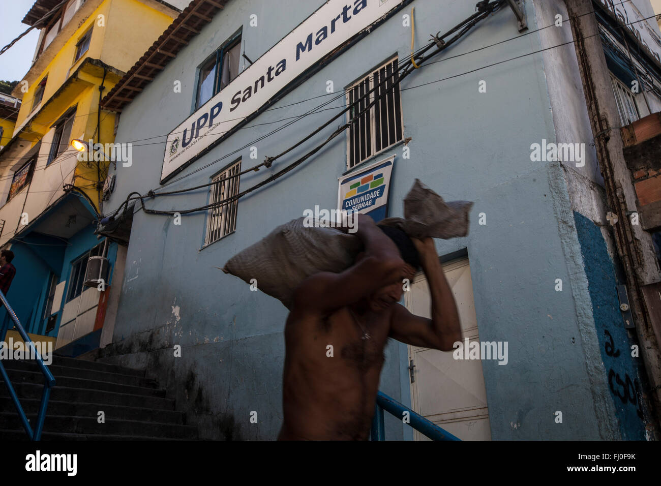 Mann geht vor dem UPP Favela Santa Marta in Rio De Janeiro, Brasilien. Seit 2008 Santa Marta eine Befriedung Polizeieinheit (Unidade de Polícia Pacificadora, auch als Befriedung Polizeieinheit übersetzt), abgekürzt UPP, Strafverfolgung und Sozialdienste Programm Rückgewinnung von Banden von Drogendealern kontrollierte Gebieten, häufiger Favelas, abzielt. Stockfoto