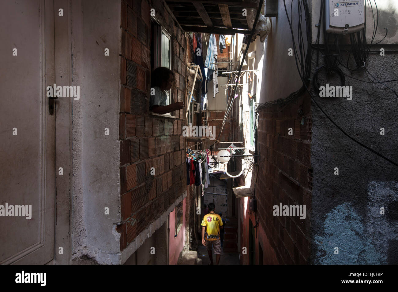 Kind am Fenster in einen schmalen Weg am Favela Santa Marta, Rio De Janeiro, Brasilien - unsachgemäße Wohnung Bedingungen wegen der Verdrängung, unhygienische Zustände, schlechte Ernährung und Umweltverschmutzung, Krankheit ist weit verbreitet in den ärmeren Favelas und Kindersterblichkeit ist hoch. Stockfoto