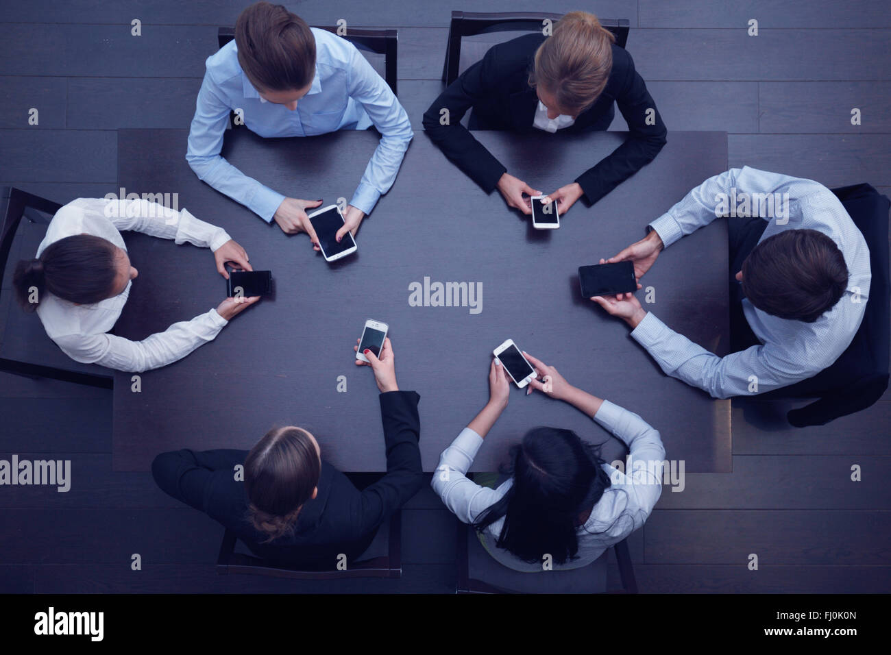 Geschäftsleute mit Smartphones sitzen um den Tisch, Ansicht von oben Stockfoto