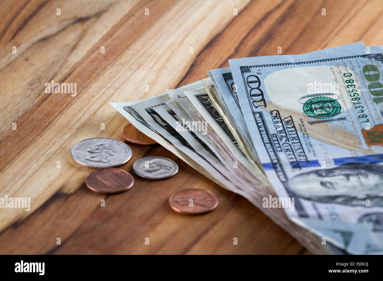 Amerikanische Währung auf einem Holztisch mit Wechsel neben den Haufen Geld Stockfoto