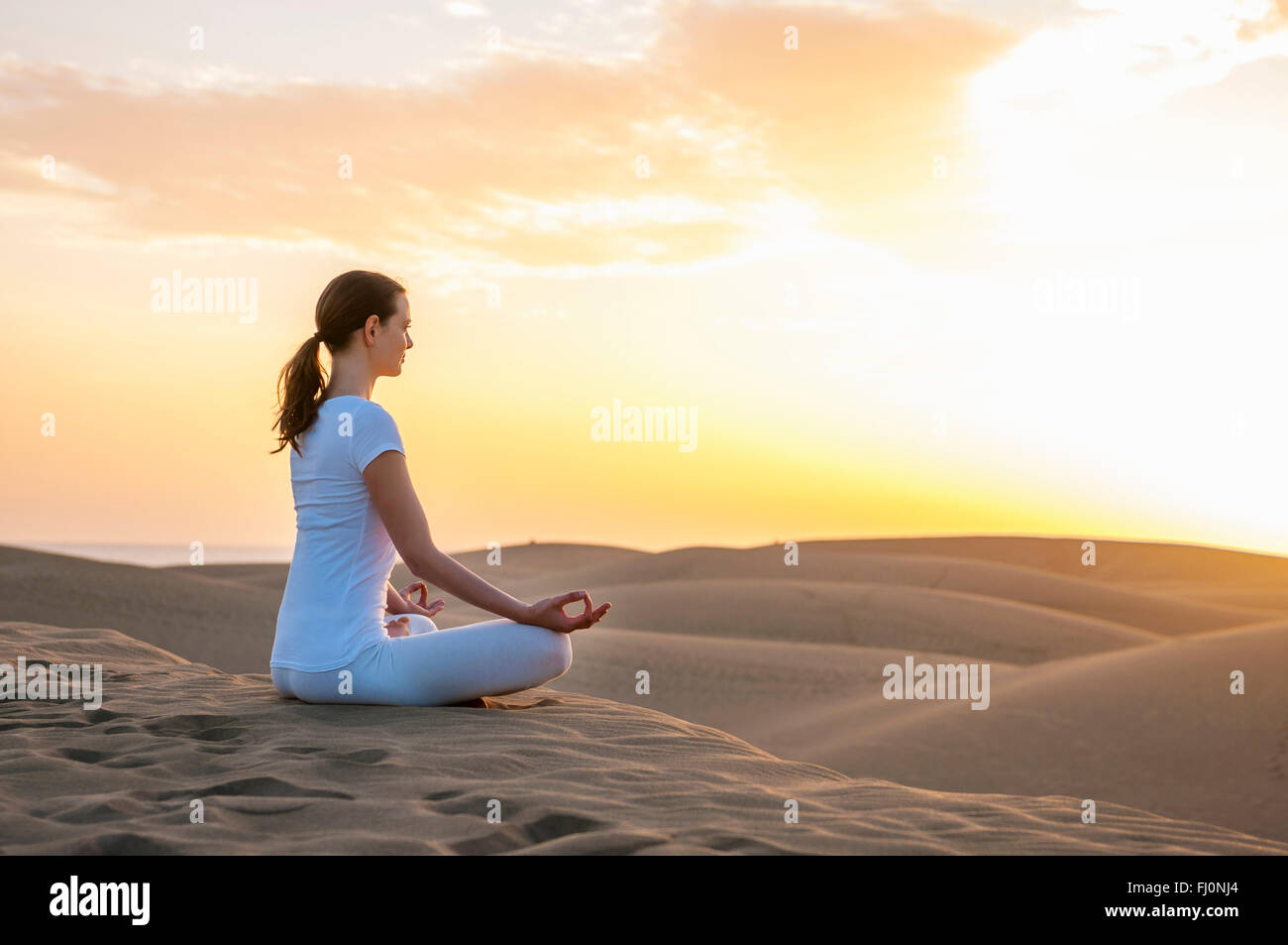 Frau praktizieren Yoga auf Sanddünen Stockfoto