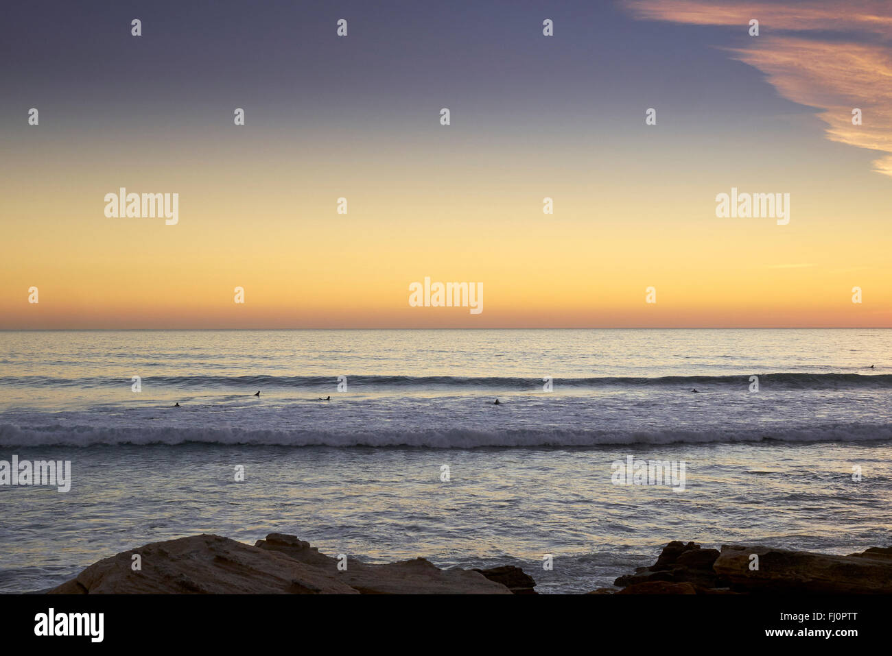 Blick auf den Sonnenuntergang von dem kleinen Fischerdorf Taghazout - Marokko. Surfer, die darauf warten, den letzten der Wellen zu fangen. Stockfoto
