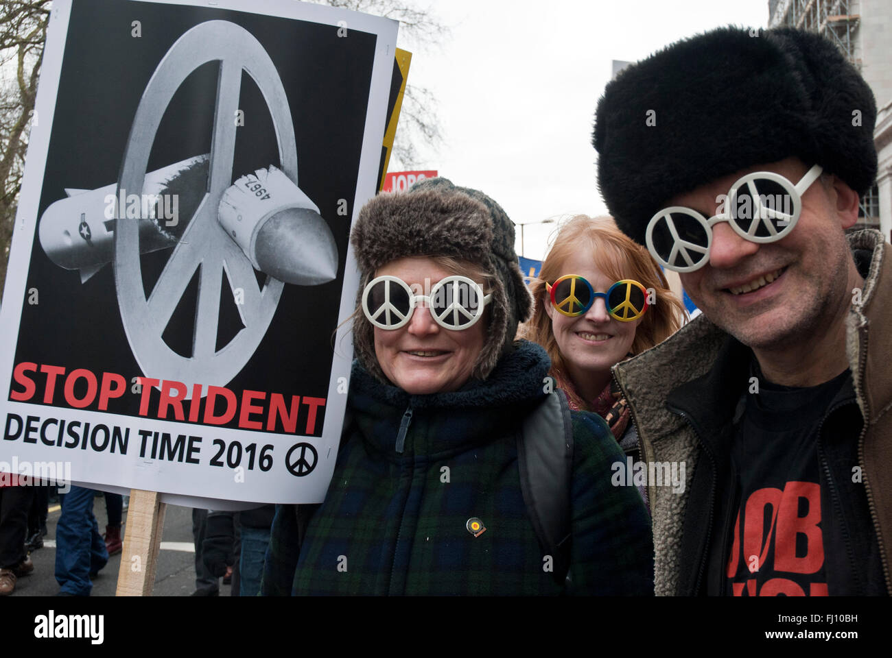 London UK. Demonstranten auf der Anti-Trident-Demonstration tragen "Ban the Bomb" symbol Brille, tragen Plakat "Trident zu stoppen" Stockfoto
