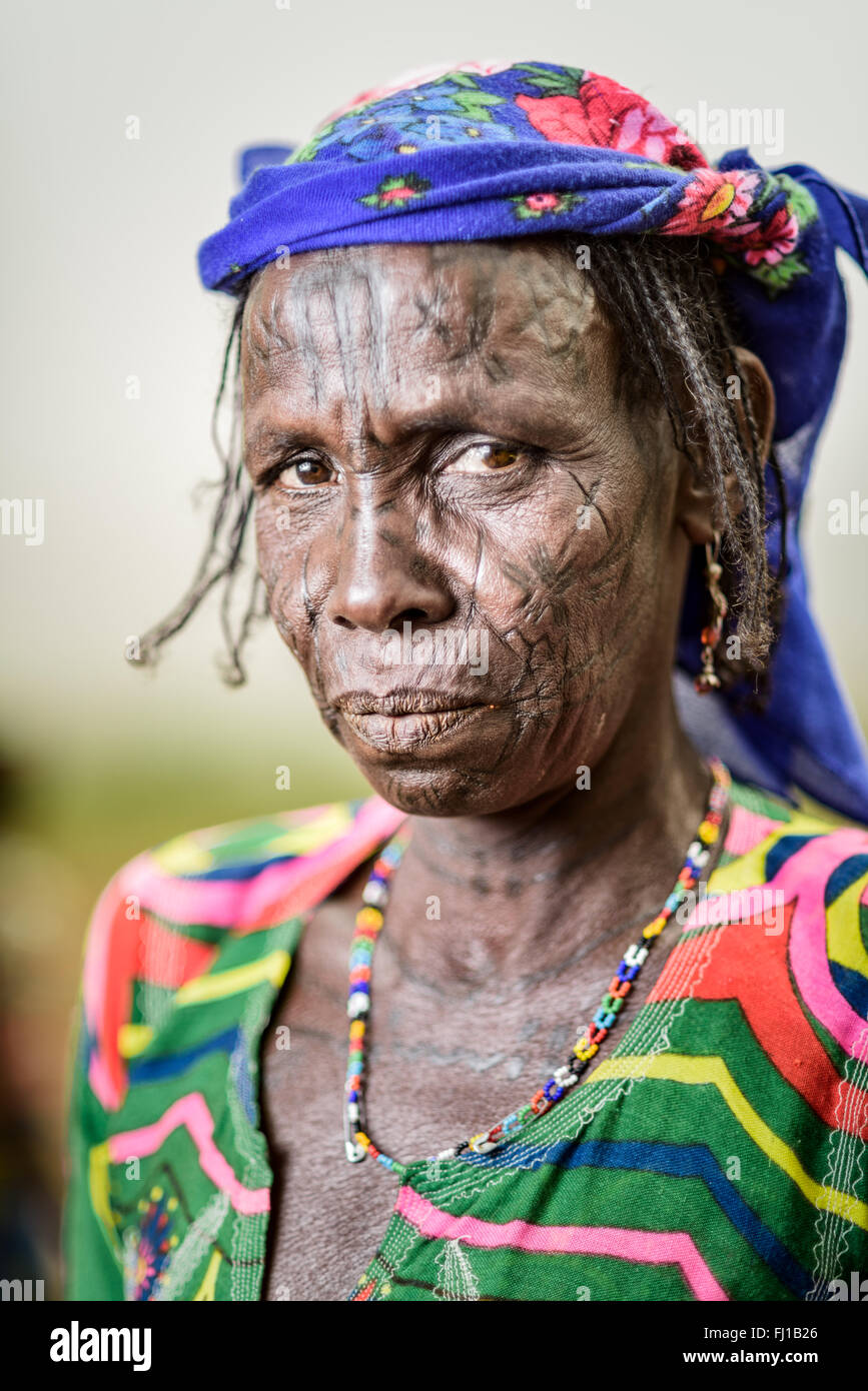 Porträt einer Frau Mbororo mit Narben im Gesicht in ein sehr farbenfrohes Outfit gekleidet. Stockfoto