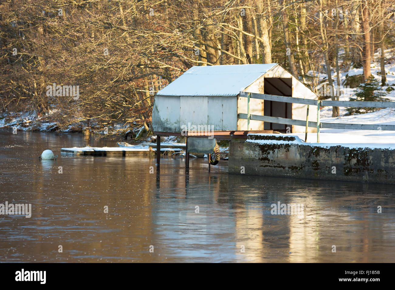 Eine kleine provisorische Bootshaus verlassen am Flussufer. Schnee auf dem Boden. Stockfoto