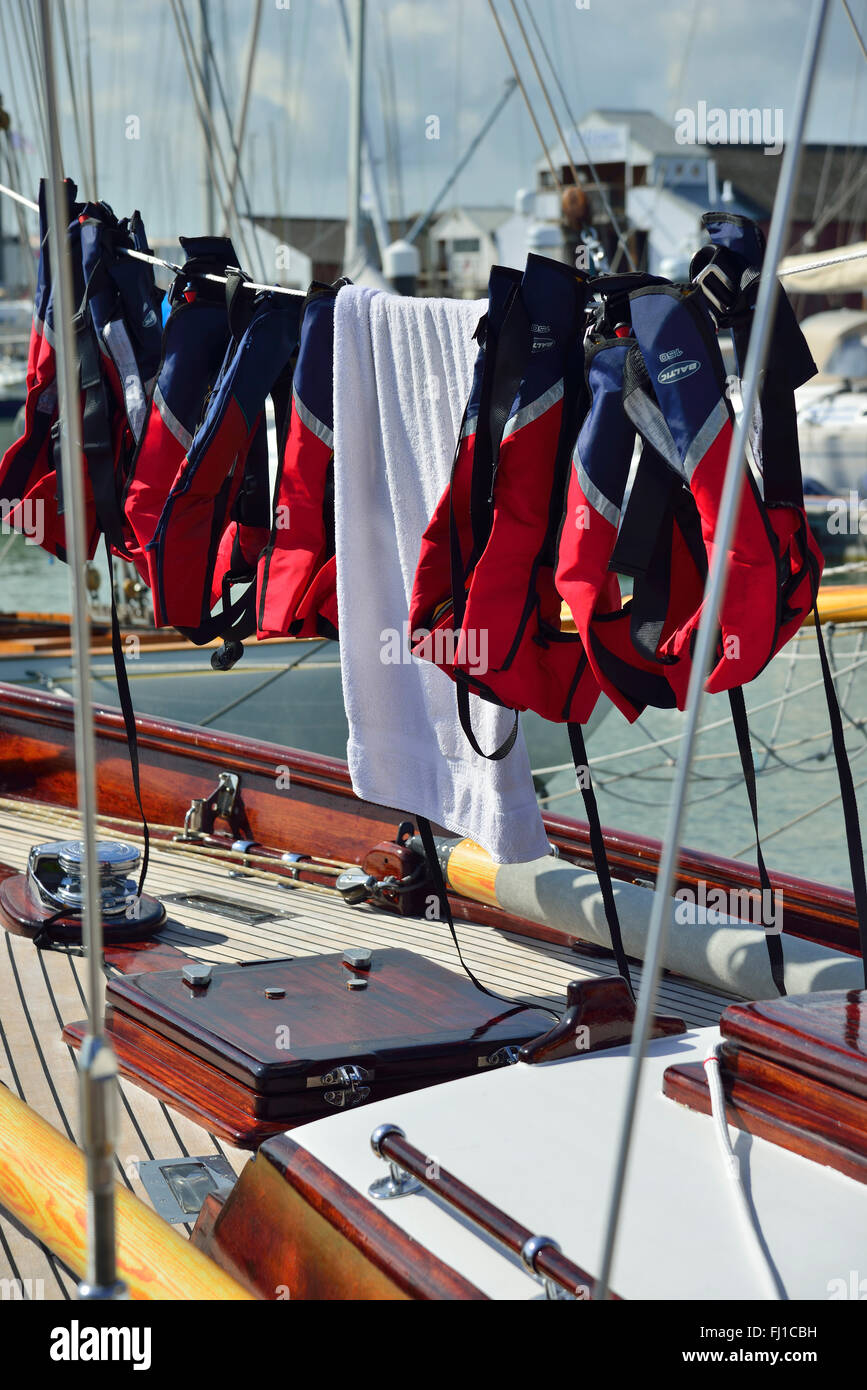 Schwimmwesten, die zum Trocknen auf der Yacht in Cowes Marina, Isle of Wight, Hampshire, England, Großbritannien aufgereiht wurden Stockfoto