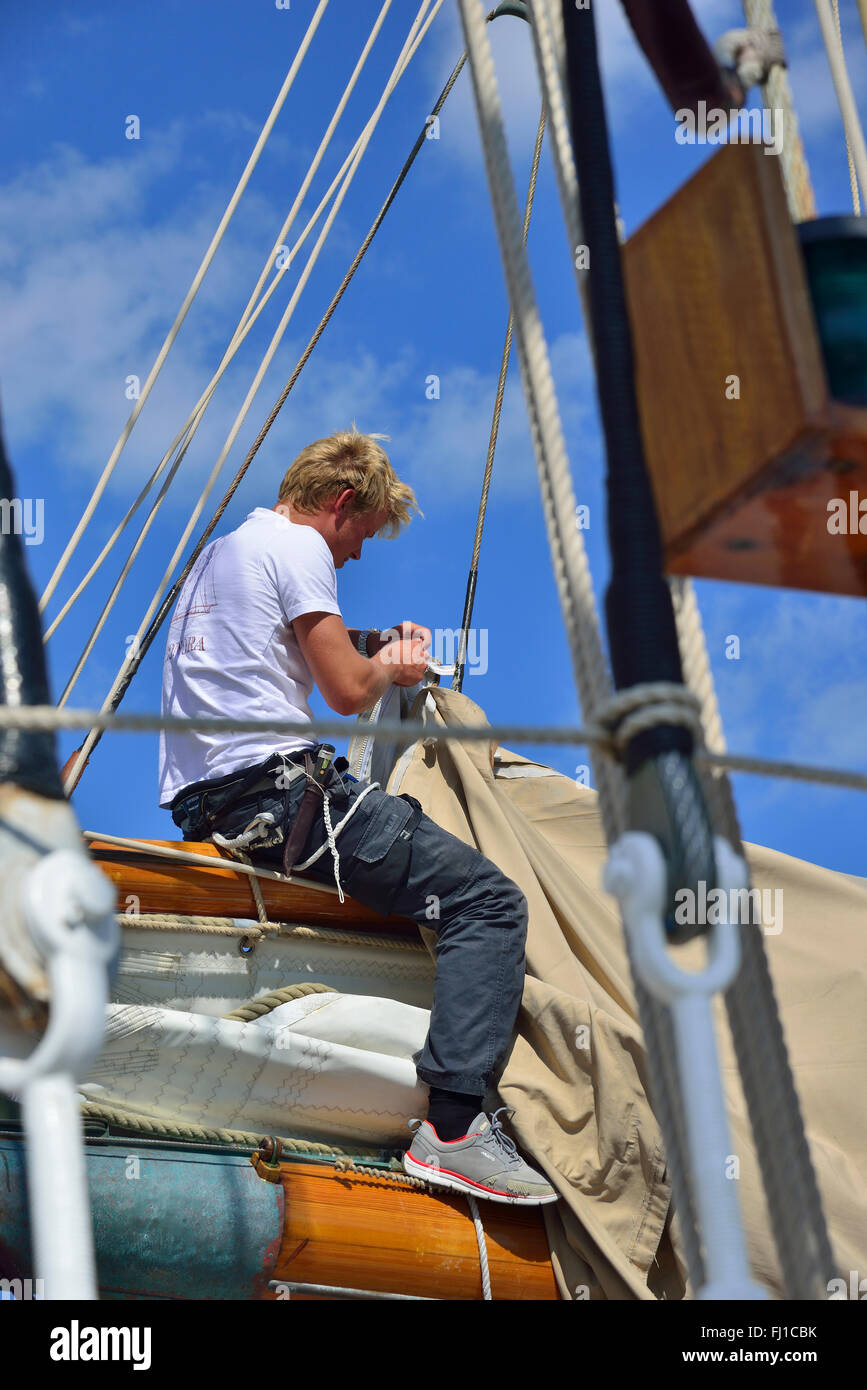 Seemann sitzt rittlings auf die wichtigsten Reparaturen zu einem Segel an Bord eines Holz- classic Yacht während klassische Woche, Cowes, Isle of Wight, Großbritannien, England Stockfoto