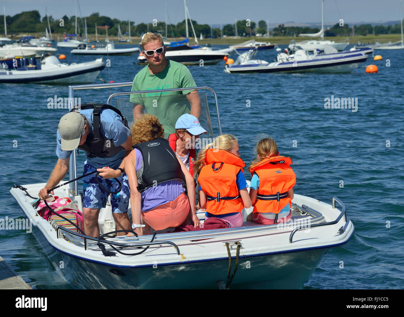 Familie mit Kindern, die das Tragen von Schwimmwesten, Leinen los aus Itchenor Quay, Chichester Harbour, West Sussex, England, UK Stockfoto