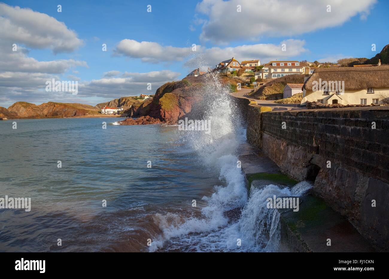 Wellen, die gegen den Deich Hope Cove, Devon, England Stockfoto