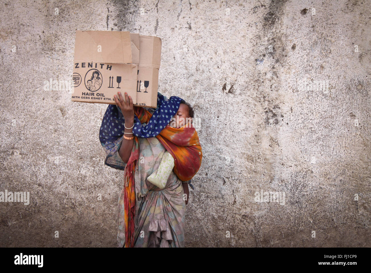 Eine Frau, die Bettler in den Straßen von Harar verbirgt ihr Gesicht mit einem Stück Karton und ihrem schlafenden Baby, Äthiopien Stockfoto