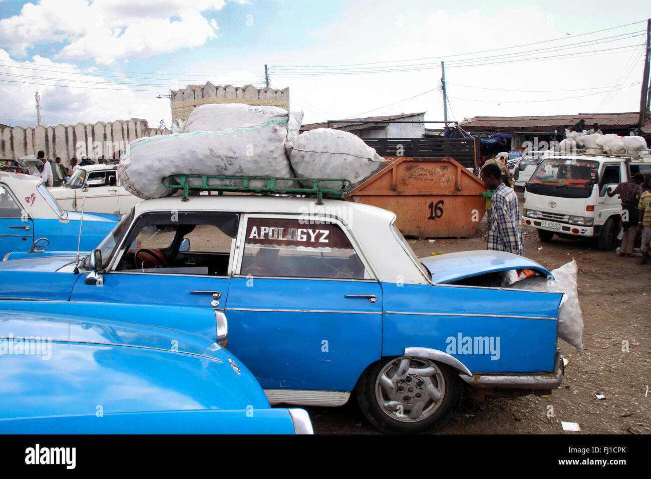 Parkplatz voll von blauen Taxis/Autos/Kabinen am Eingang der Altstadt von Harar, Äthiopien, mit 'Entschuldigen' auf Glas geschrieben Stockfoto